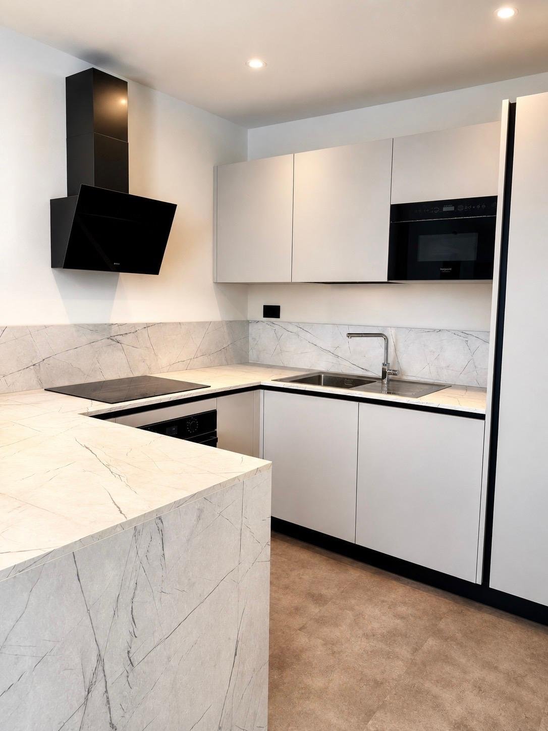 Cucina contemporanea bianca con dettagli neri e rivestimento effetto marmo